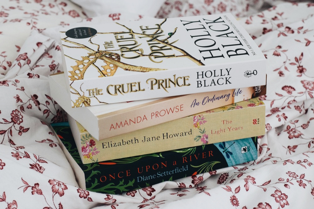 stack of books on floral bedding
